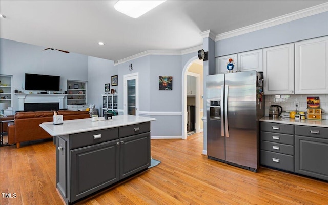 kitchen featuring light wood finished floors, gray cabinetry, stainless steel fridge with ice dispenser, light countertops, and arched walkways