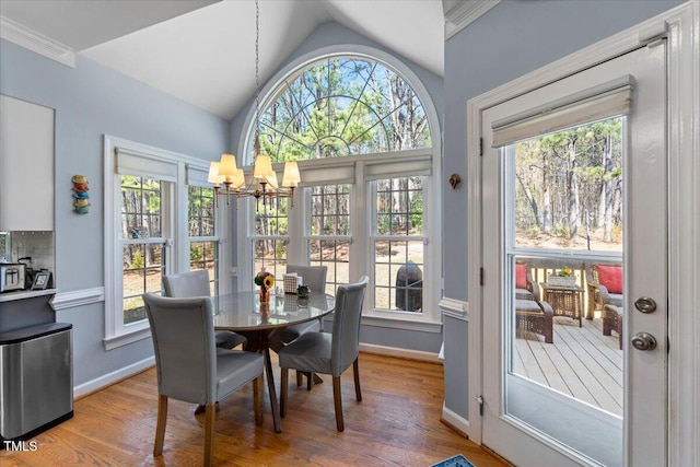 dining room featuring a notable chandelier, baseboards, light wood-style floors, and vaulted ceiling