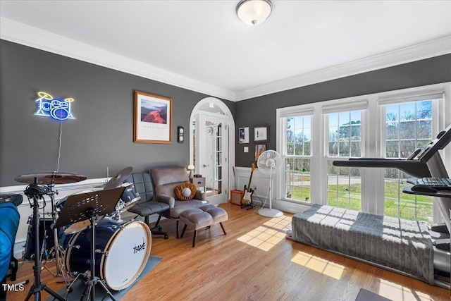 playroom featuring wood finished floors, arched walkways, and ornamental molding