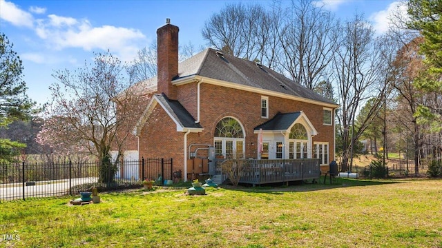 rear view of house with brick siding, fence, a wooden deck, a chimney, and a yard