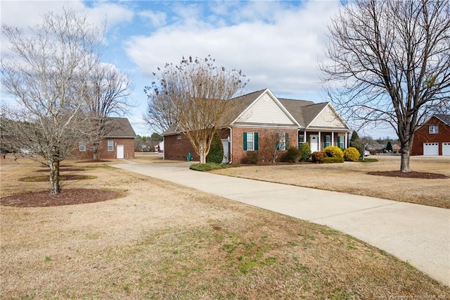 view of front of property featuring a front yard, brick siding, and driveway