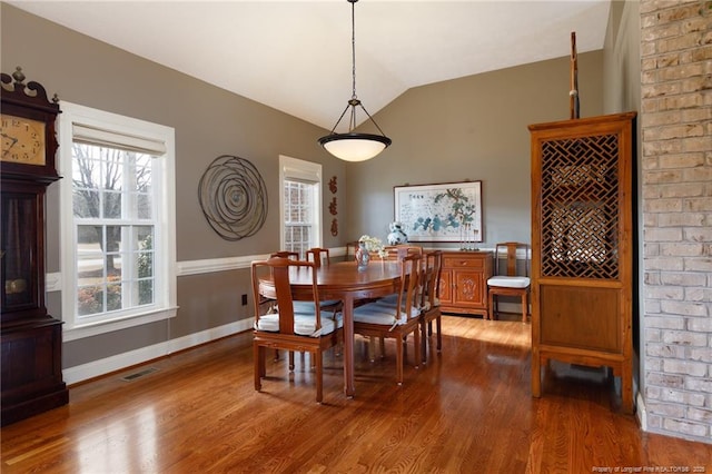 dining area featuring dark wood finished floors, vaulted ceiling, baseboards, and visible vents