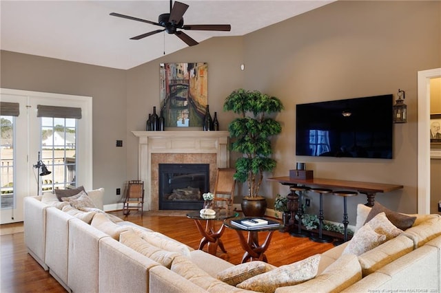 living area featuring lofted ceiling, a fireplace, wood finished floors, and a ceiling fan