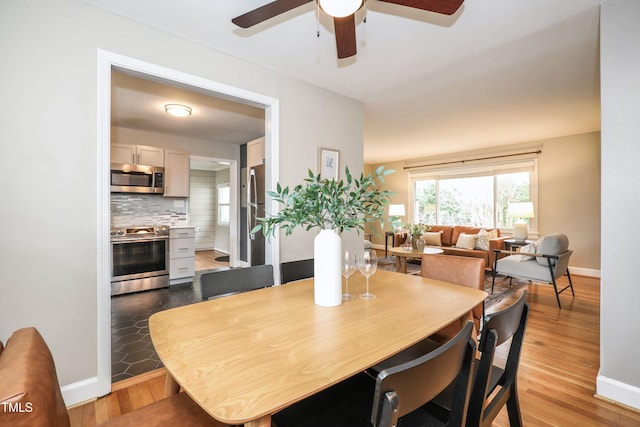 dining area with wood finished floors, a ceiling fan, and baseboards