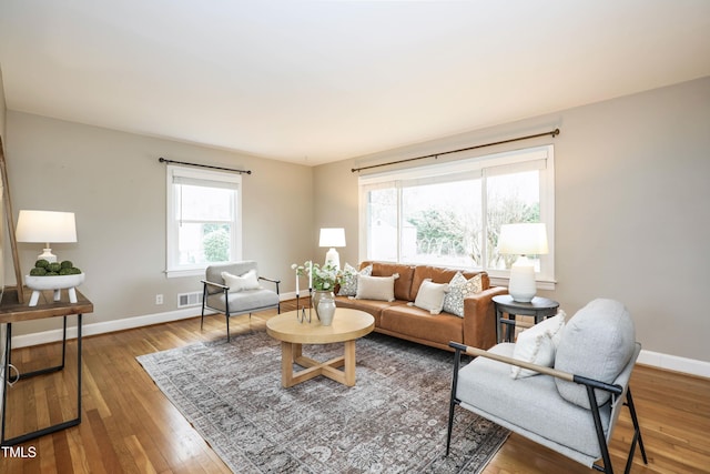 living area with hardwood / wood-style flooring, visible vents, and baseboards