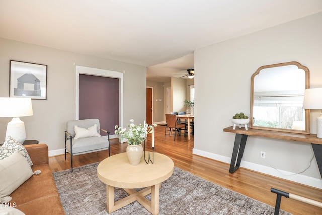 living room featuring wood finished floors, baseboards, and ceiling fan