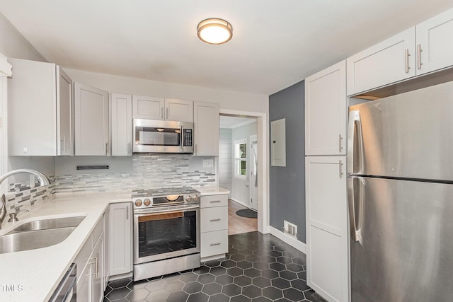 kitchen featuring backsplash, appliances with stainless steel finishes, light countertops, and a sink