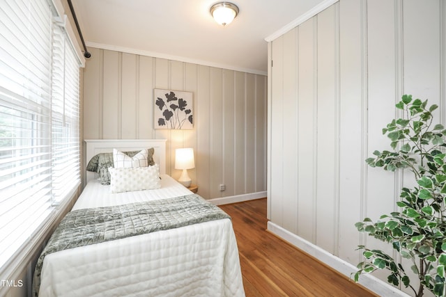 bedroom featuring wood finished floors, baseboards, and ornamental molding