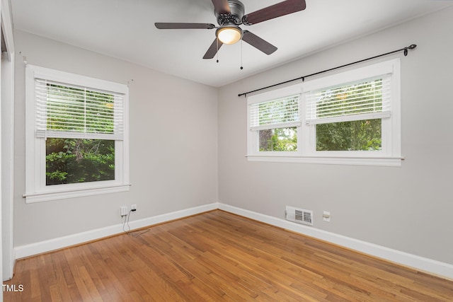 empty room with visible vents, plenty of natural light, baseboards, and light wood-style floors