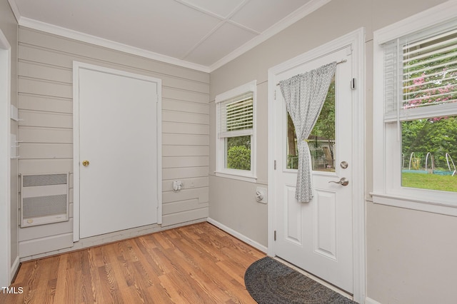 foyer with heating unit, ornamental molding, and light wood finished floors