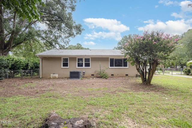 back of house with crawl space, a lawn, central AC, and fence