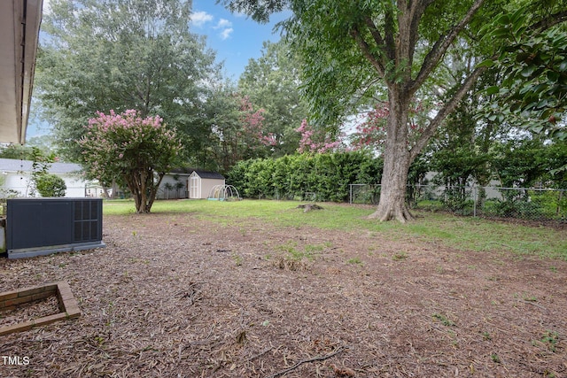 view of yard with an outdoor structure, a storage unit, central AC unit, and fence