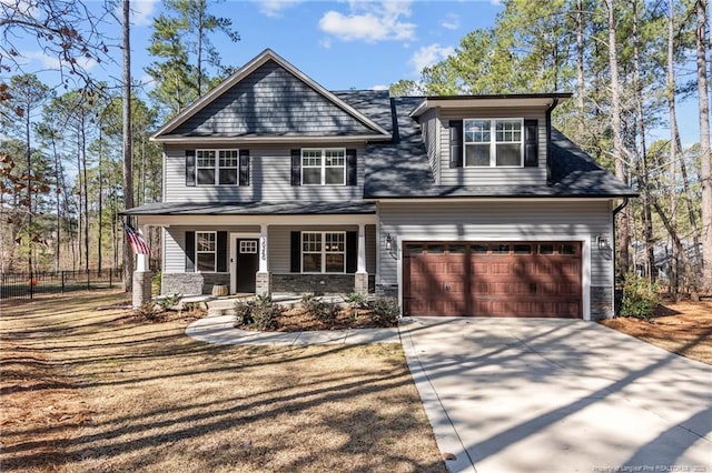 craftsman-style home with fence, a porch, concrete driveway, a garage, and stone siding