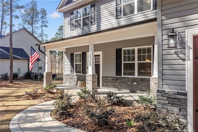 entrance to property featuring a porch and stone siding