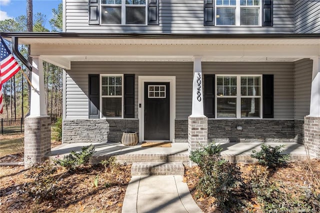 doorway to property with a porch and stone siding