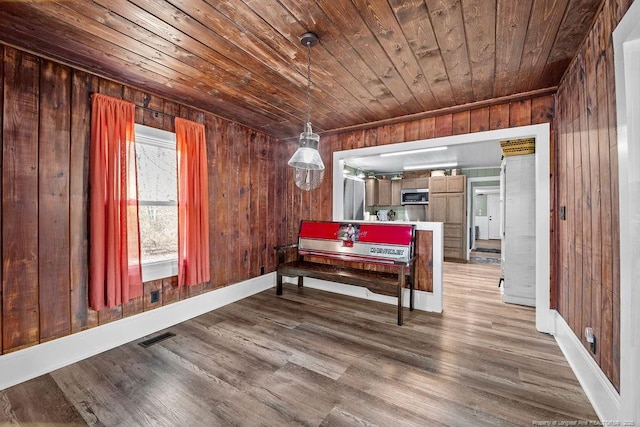 bedroom featuring visible vents, wood finished floors, wood walls, wooden ceiling, and baseboards