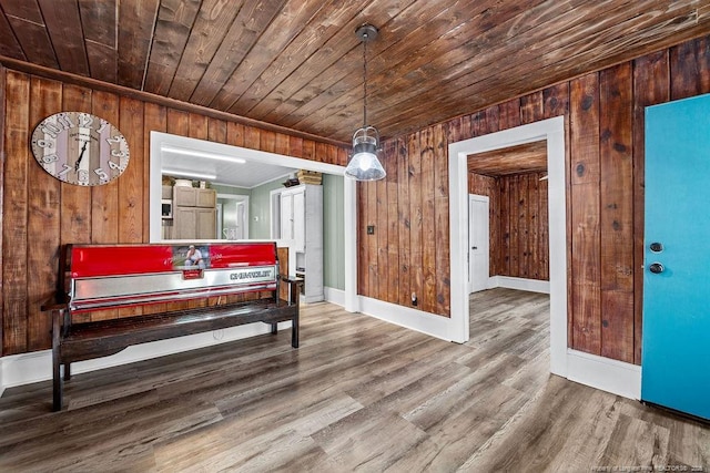 interior space with baseboards, wood ceiling, wood finished floors, and wood walls