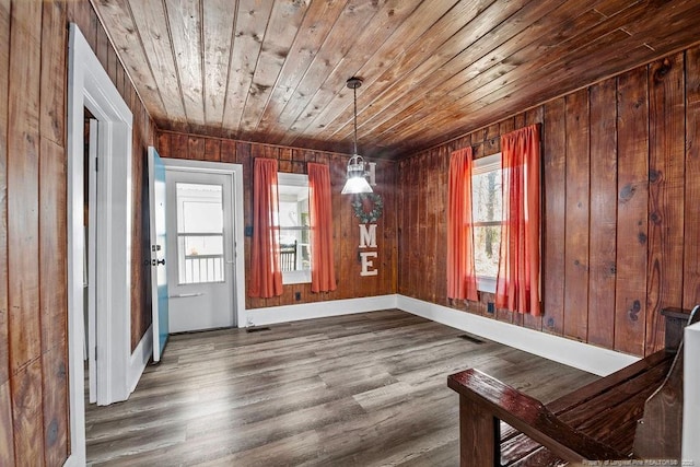 unfurnished dining area featuring dark wood finished floors, wooden ceiling, visible vents, and a wealth of natural light