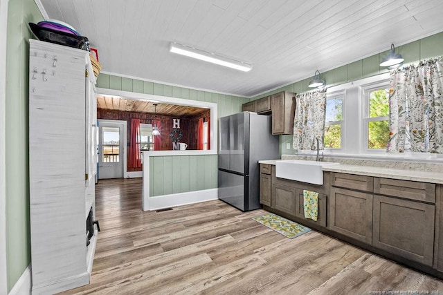 kitchen with a sink, a wealth of natural light, light wood-style flooring, and freestanding refrigerator