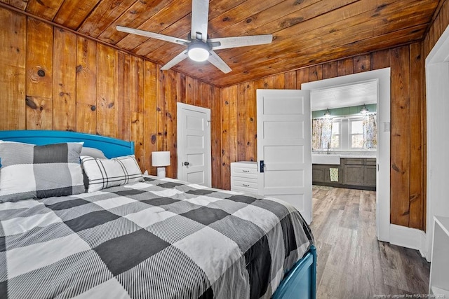 bedroom featuring a ceiling fan, a sink, wood finished floors, wood walls, and wooden ceiling