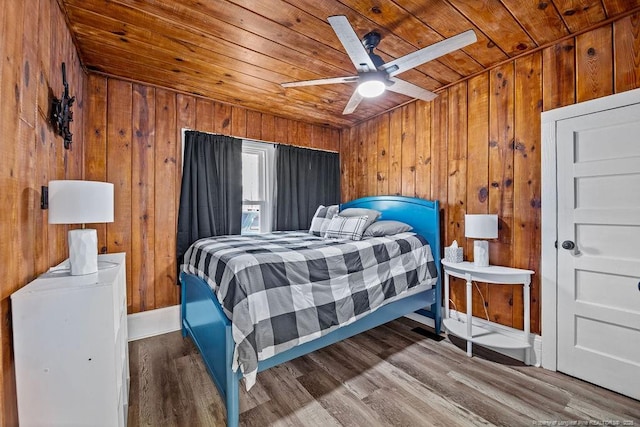 bedroom featuring a ceiling fan, wooden ceiling, wooden walls, and wood finished floors