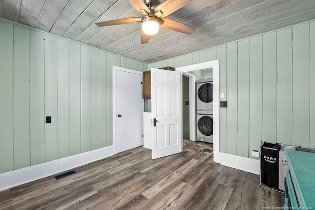 bedroom with visible vents, dark wood-type flooring, stacked washer and dryer, baseboards, and ceiling fan