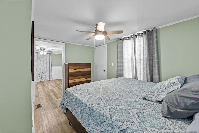 bedroom with visible vents, ceiling fan, crown molding, and light wood-style floors