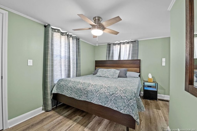 bedroom featuring crown molding, wood finished floors, baseboards, and ceiling fan