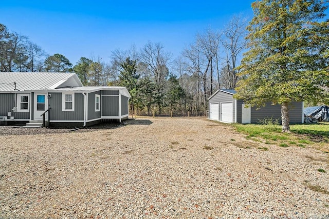 view of yard featuring a detached garage, an outdoor structure, and entry steps