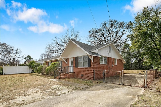 view of side of home featuring fence, brick siding, driveway, and a gate