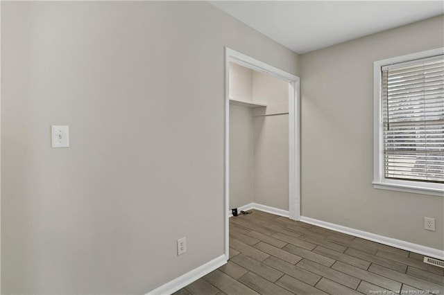 unfurnished bedroom with visible vents, dark wood-style floors, baseboards, and a closet