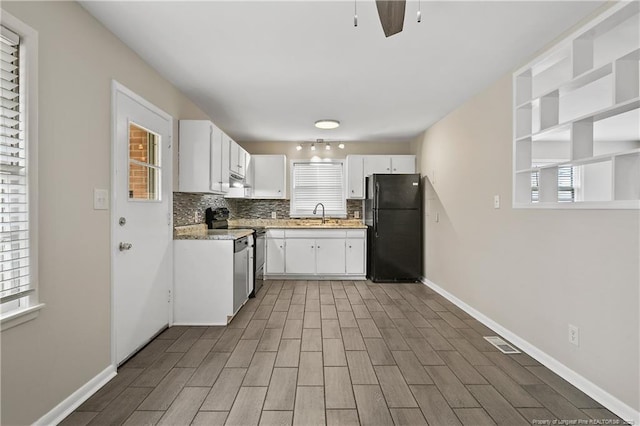 kitchen featuring visible vents, tasteful backsplash, white cabinetry, freestanding refrigerator, and range