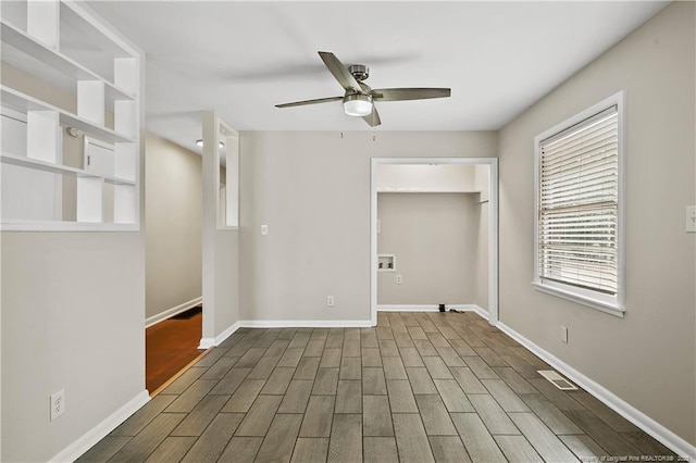 spare room featuring baseboards, wood finished floors, and ceiling fan