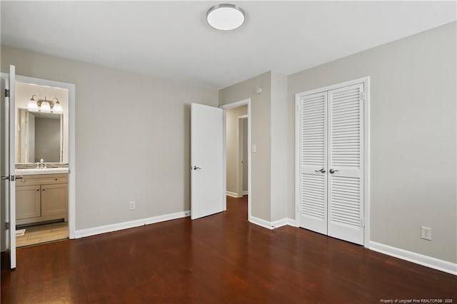 unfurnished bedroom with wood finished floors, baseboards, a closet, and a sink