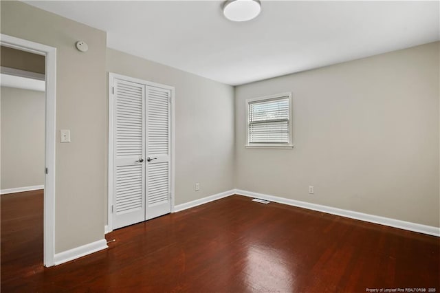 unfurnished bedroom featuring a closet, baseboards, and wood finished floors