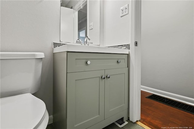 bathroom with vanity, wood finished floors, visible vents, baseboards, and toilet