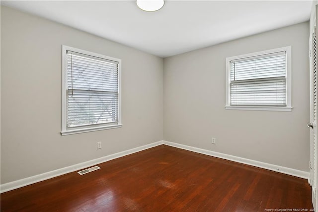 empty room with visible vents, baseboards, and wood finished floors