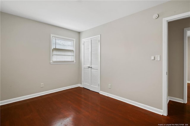 unfurnished bedroom featuring a closet, baseboards, and wood finished floors