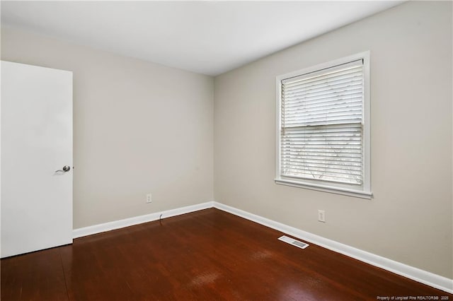 empty room with visible vents, baseboards, and wood finished floors