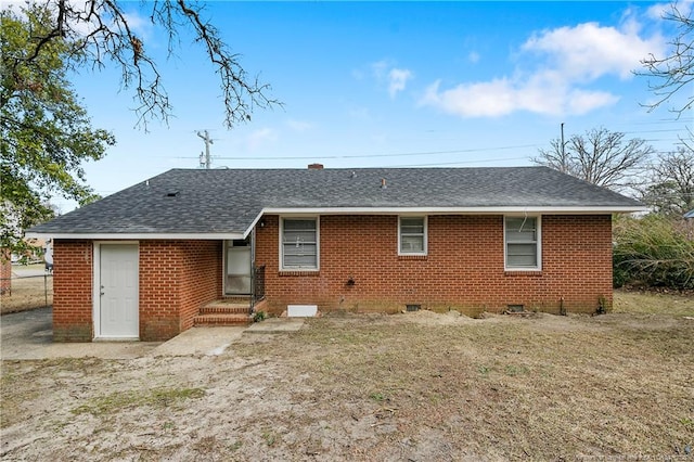 rear view of property featuring brick siding and roof with shingles