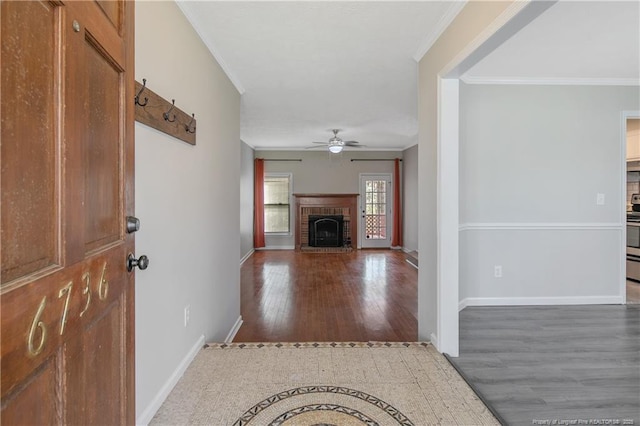 entrance foyer featuring wood finished floors, baseboards, a fireplace, ceiling fan, and crown molding