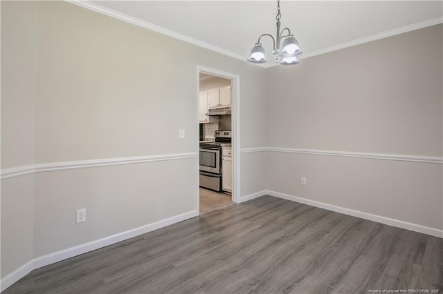 empty room featuring a notable chandelier, wood finished floors, baseboards, and ornamental molding