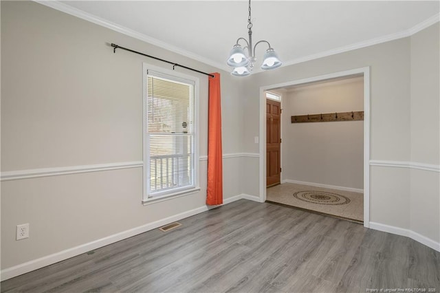 empty room featuring an inviting chandelier, crown molding, and visible vents