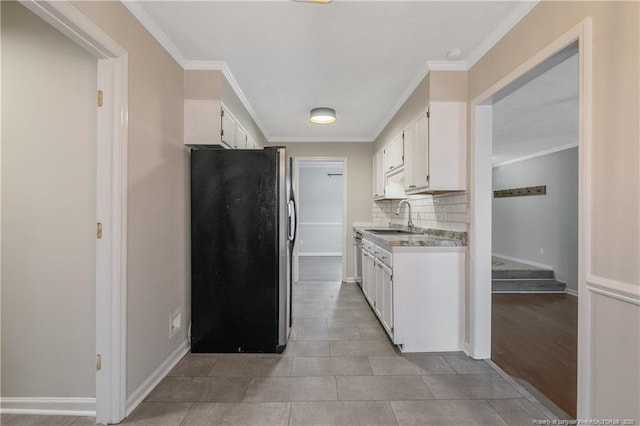 kitchen featuring backsplash, crown molding, freestanding refrigerator, white cabinets, and a sink