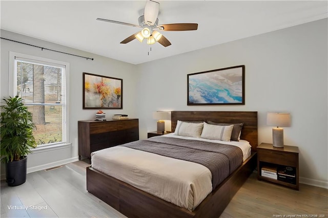 bedroom with visible vents, light wood-style flooring, a ceiling fan, and baseboards