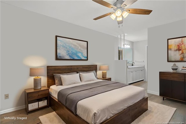 bedroom featuring a sink, baseboards, light wood-style floors, and ensuite bath