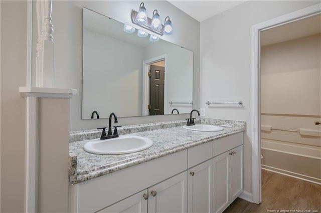 bathroom with a sink, wood finished floors, and double vanity