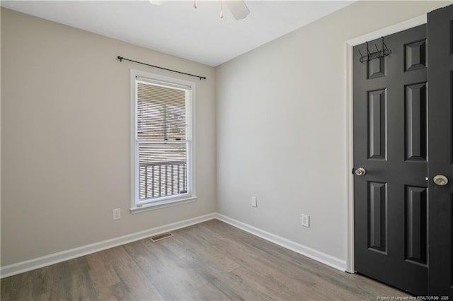 empty room featuring ceiling fan, wood finished floors, visible vents, and baseboards