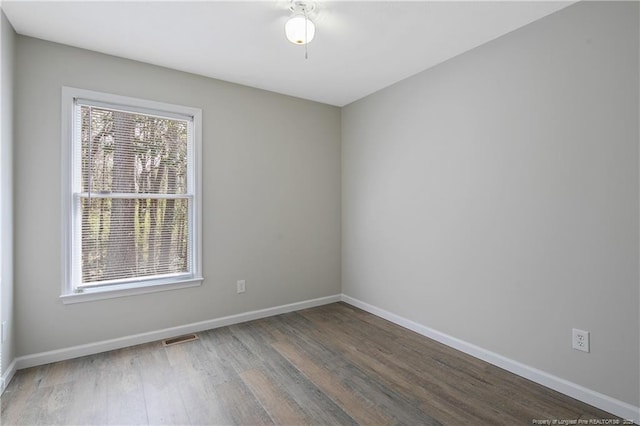 empty room with visible vents, baseboards, and wood finished floors