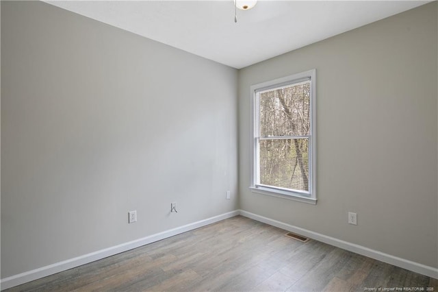 spare room with visible vents, baseboards, and wood finished floors